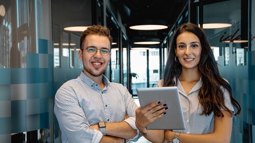 jonge man met bril en jonge vrouw met ipad in kantoor