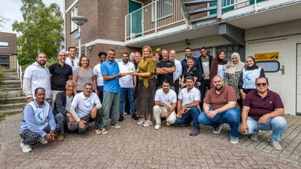 De teams van De Sleutels en Stichting Sakiena poseren met taart om hun samenwerking te vieren
