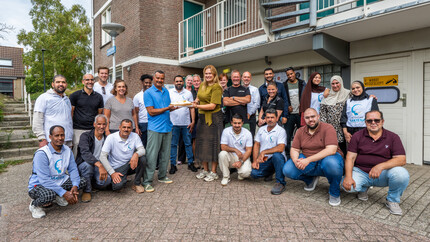 De teams van De Sleutels en Stichting Sakiena poseren met taart om hun samenwerking te vieren